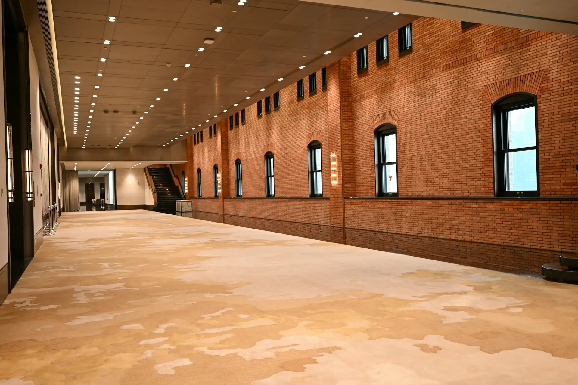 Salão de eventos vazio, com paredes de tijolo e o piso livre antes da montagem.
